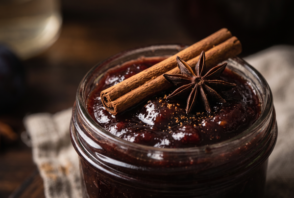 Prim-plan cu dulceață de prune condimentată în borcan, cu băț de scorțișoară și anason stelat